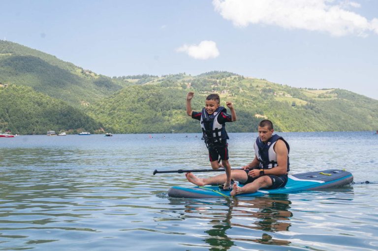 The boy is jumping from the SUP board into the water