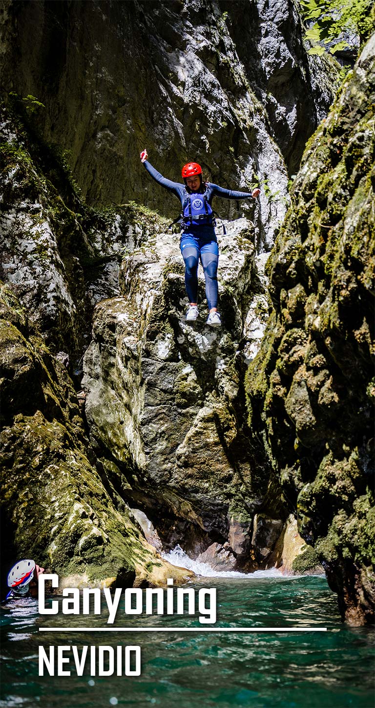Jumping into the water from a cliff in the Nevidio Canyon. Text: Canyoning Nevidio.