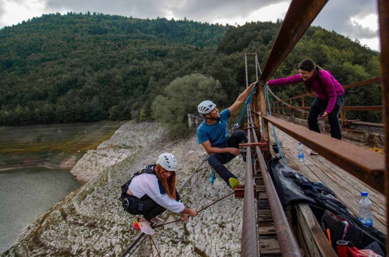Three people on a bridge.
