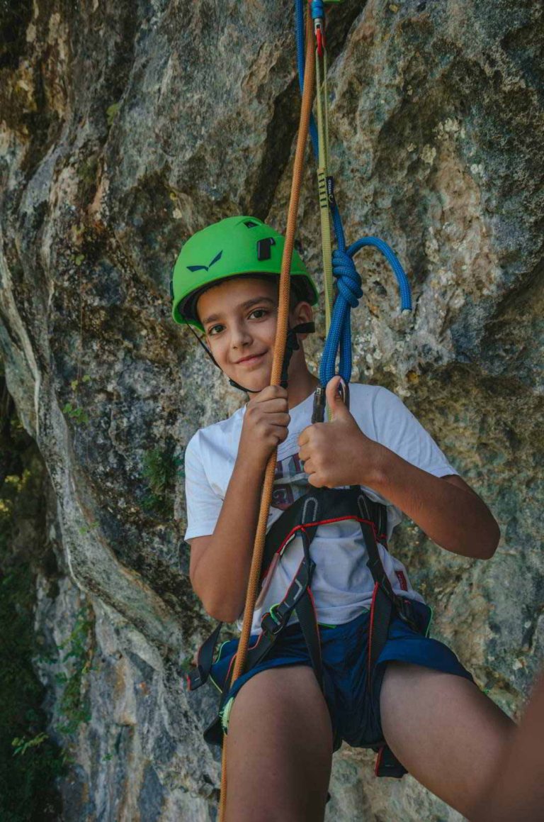 Dečak od 7 godina sa kacigom na glavi i opremom za spustnji niz uže