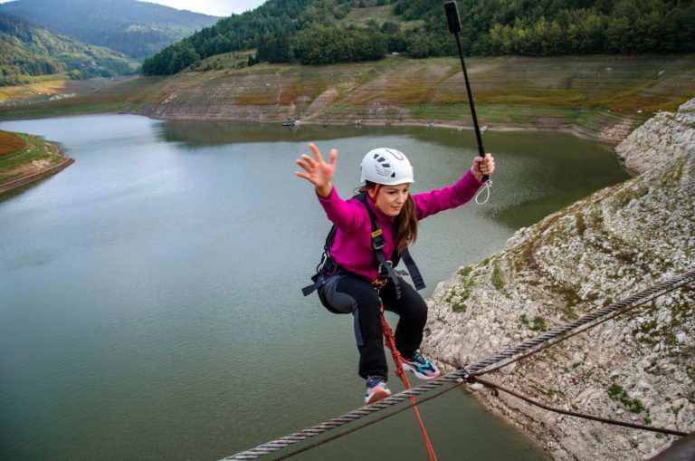 The girl with a helmet on her head is jumping from the bridge.