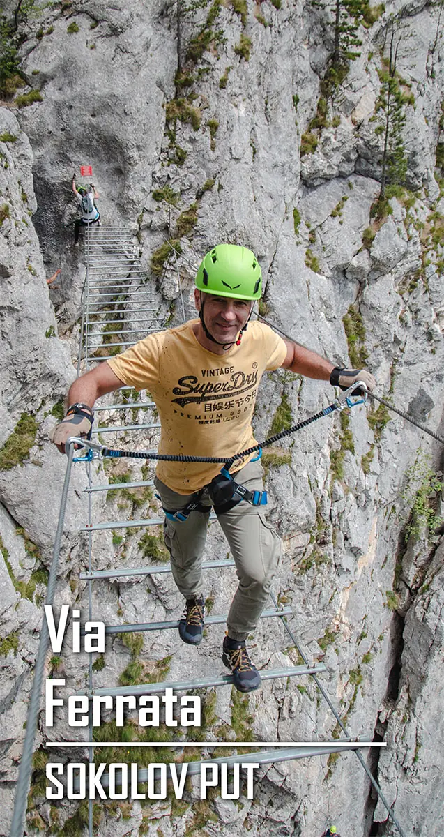 Muskarac prelazi preko žičanog mosta na via ferati Crvene stene na Romaniji, u blizini istiomenog Planinarskog Doma uz upotrebu sigurnosne opreme (kaciga, pojas i ferata apsorber)